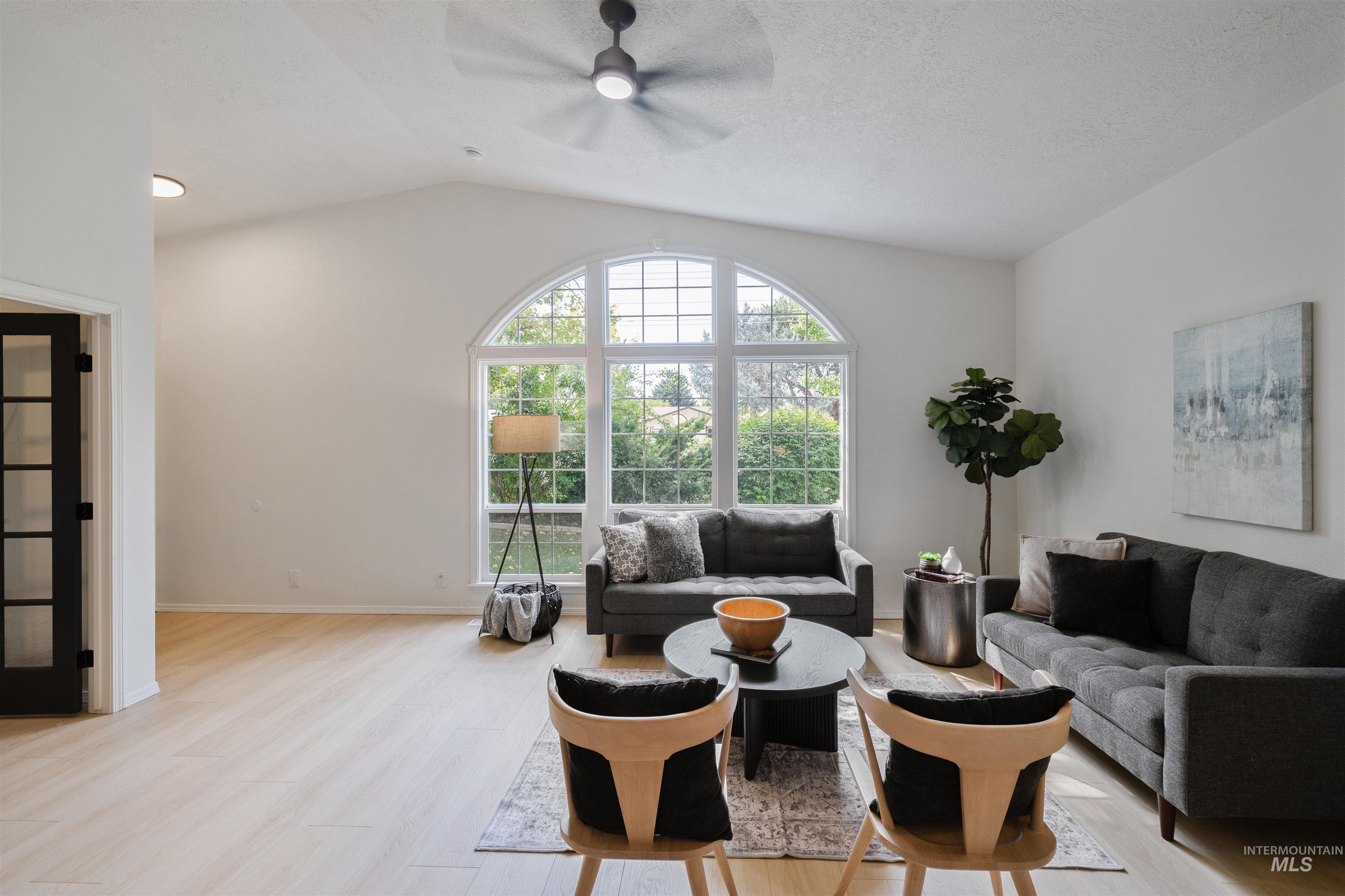 Living area with lofted ceiling, light wood-type flooring, and ceiling fan
