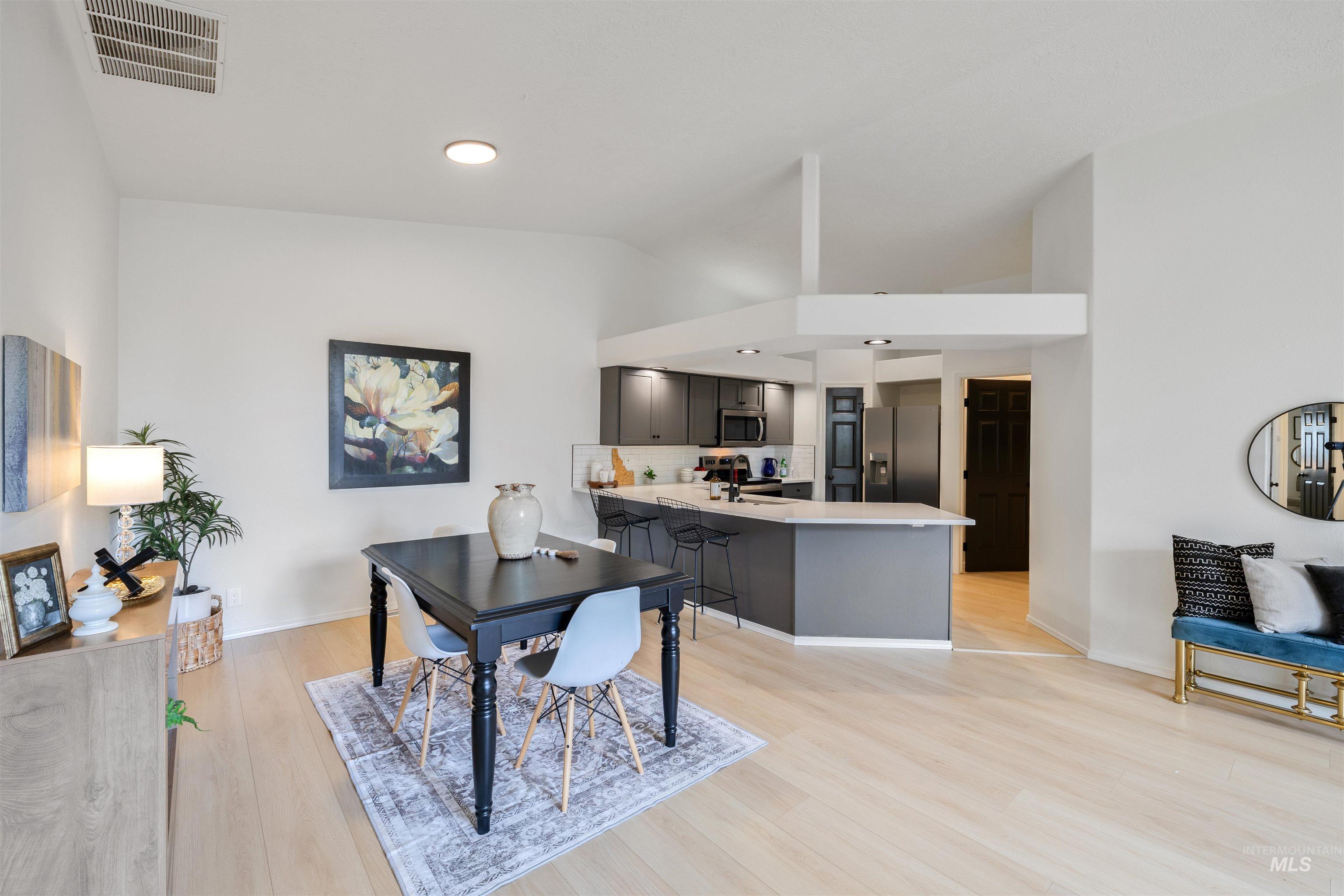 Dining space with light wood-style flooring, vaulted ceiling, and recessed lighting