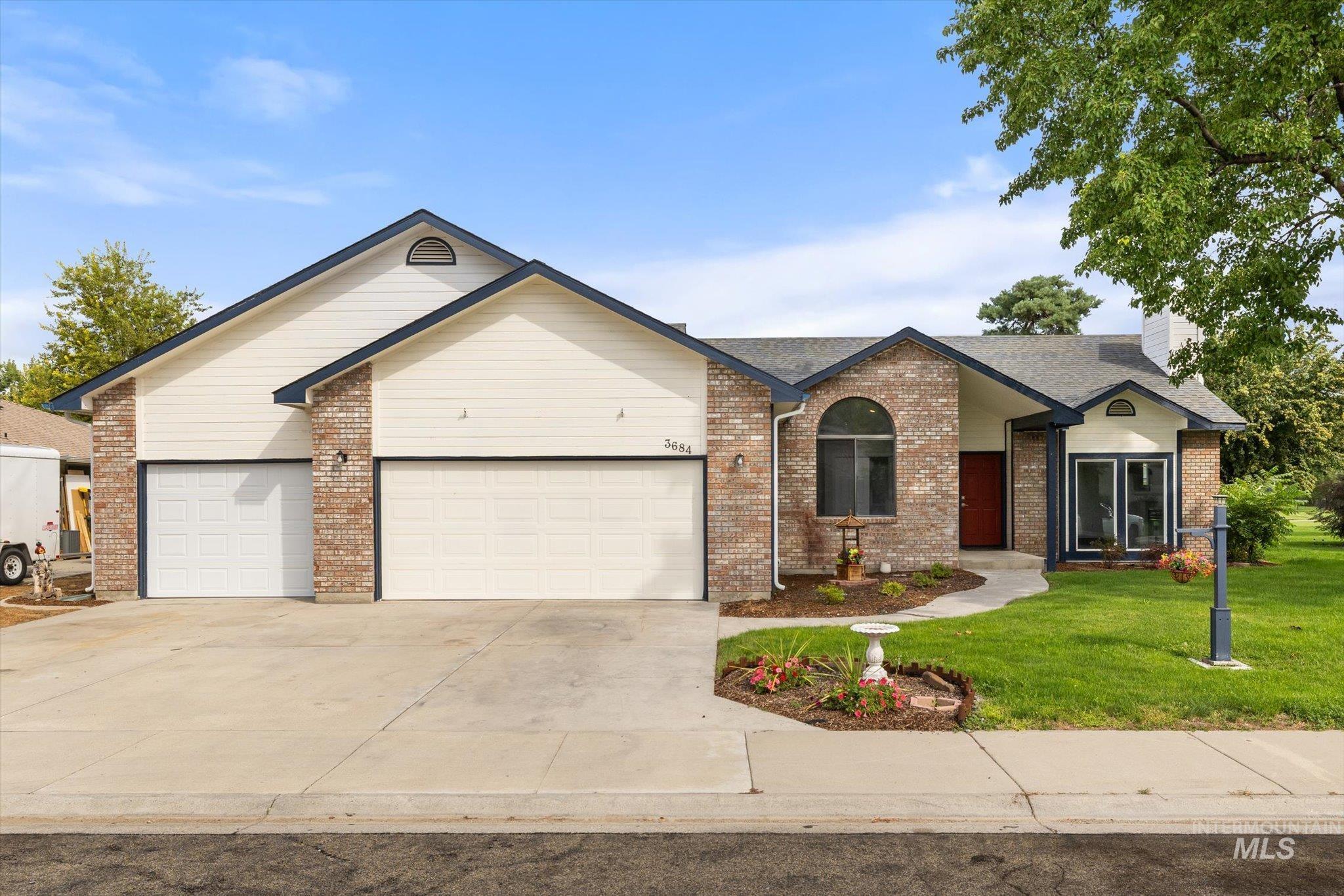 Ranch-style home with driveway, a garage, a front lawn, brick siding, and a chimney