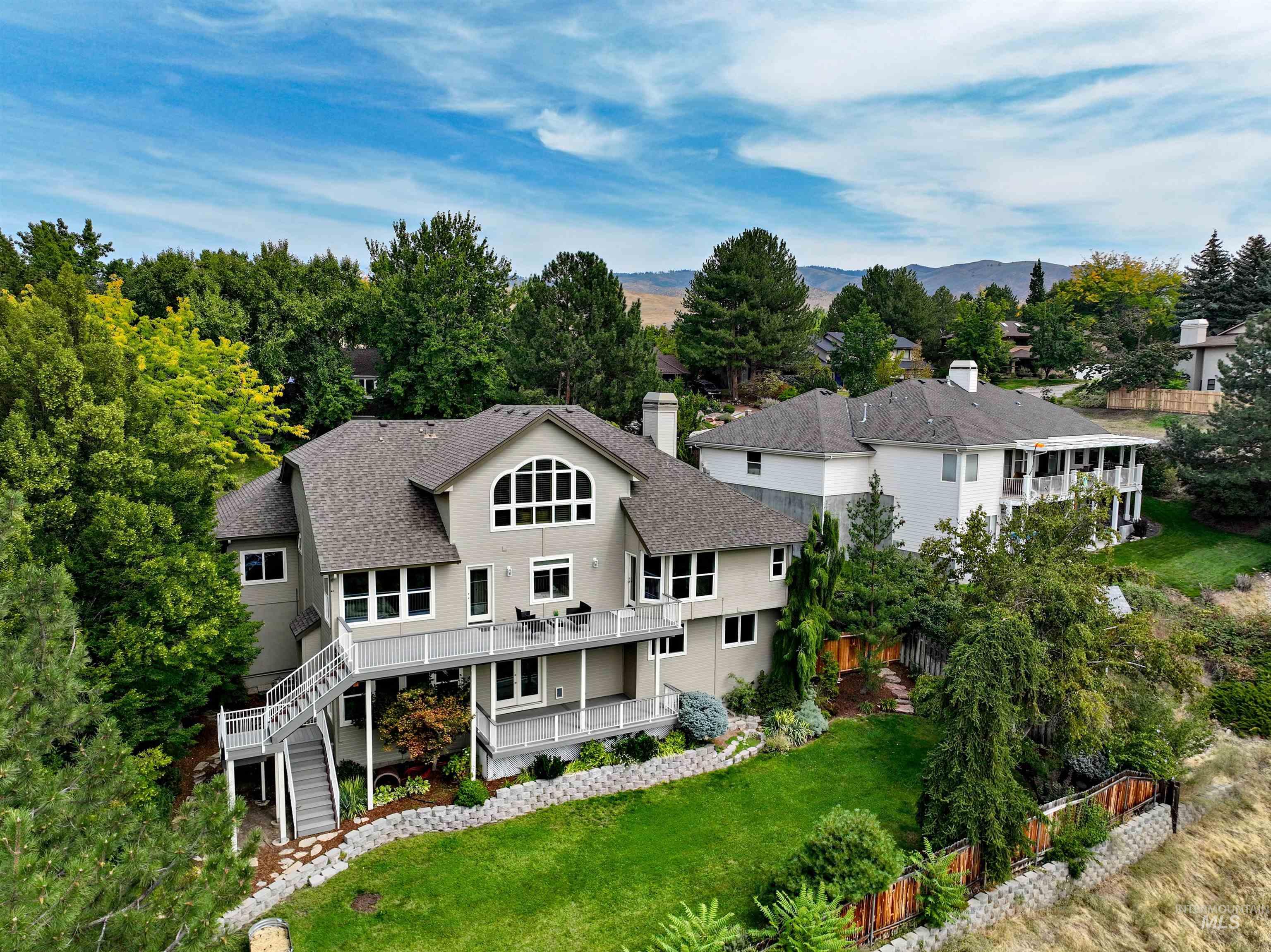 Rear view of property featuring stairs, a chimney, a shingled roof, a deck with mountain view, and view of wooded area