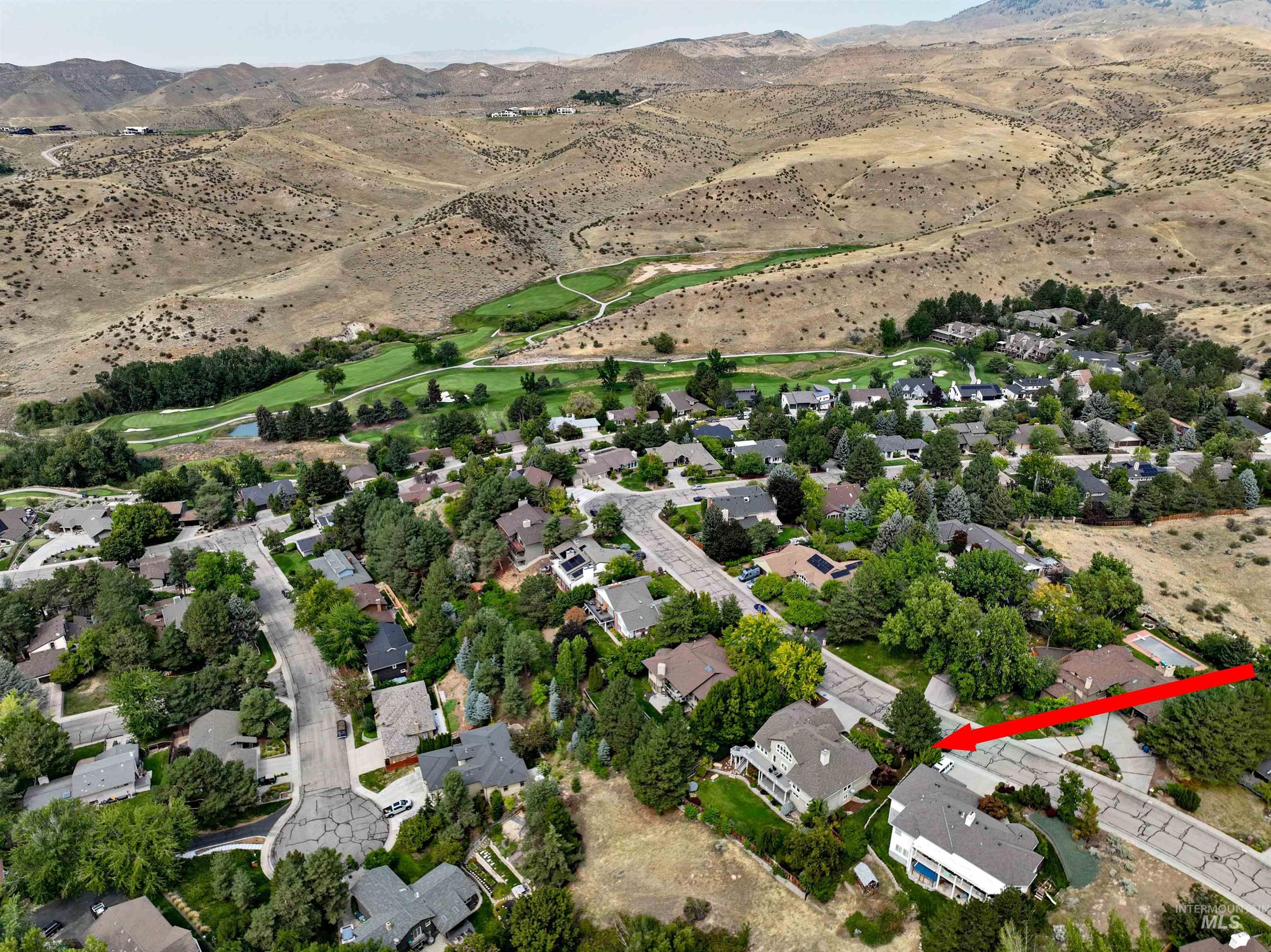 Aerial view of property and surrounding area featuring nearby suburban area and a mountain backdrop