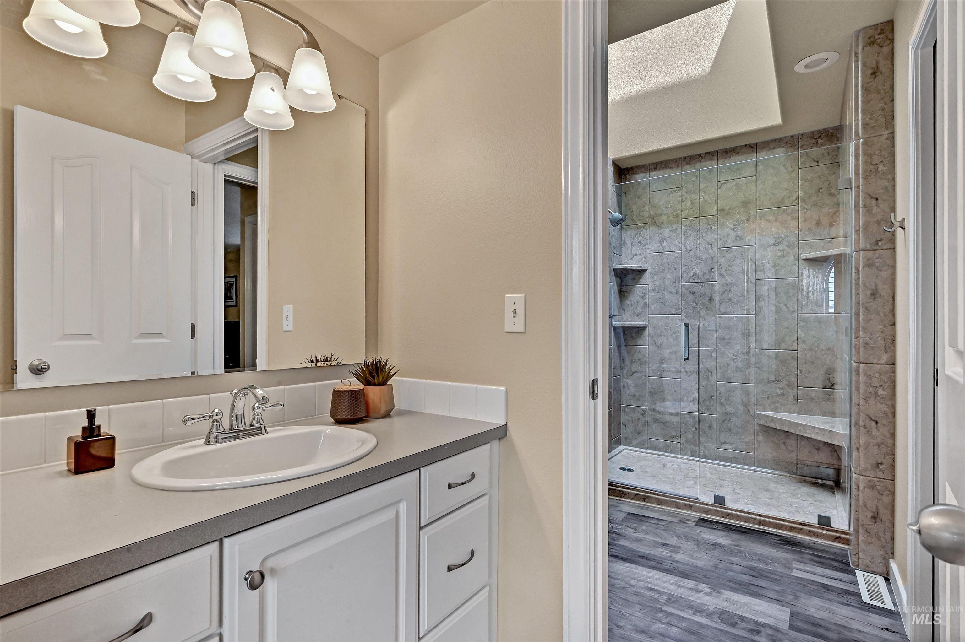 Full bathroom featuring vanity, a stall shower, and wood finished floors
