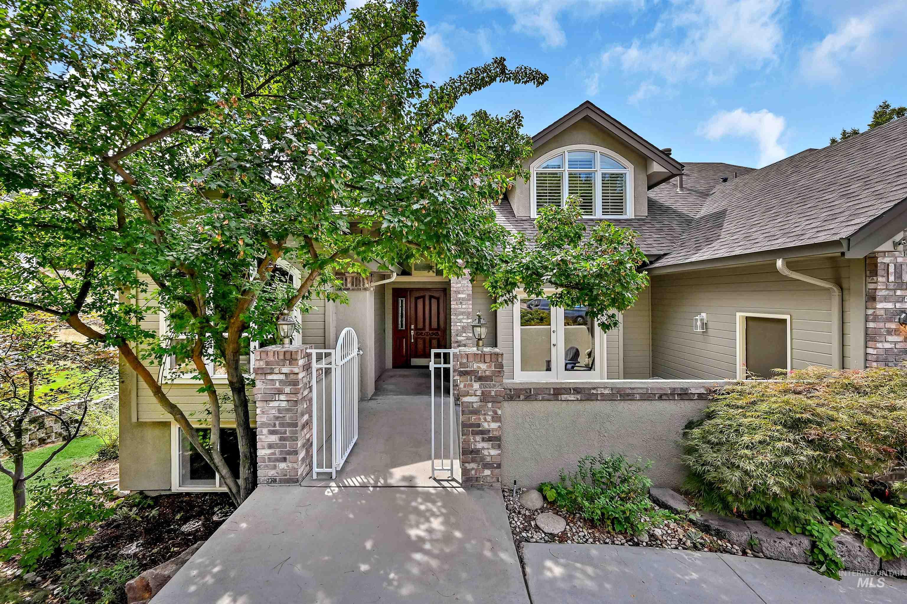 View of front of house featuring a gate, a shingled roof, a fenced front yard, and stone siding
