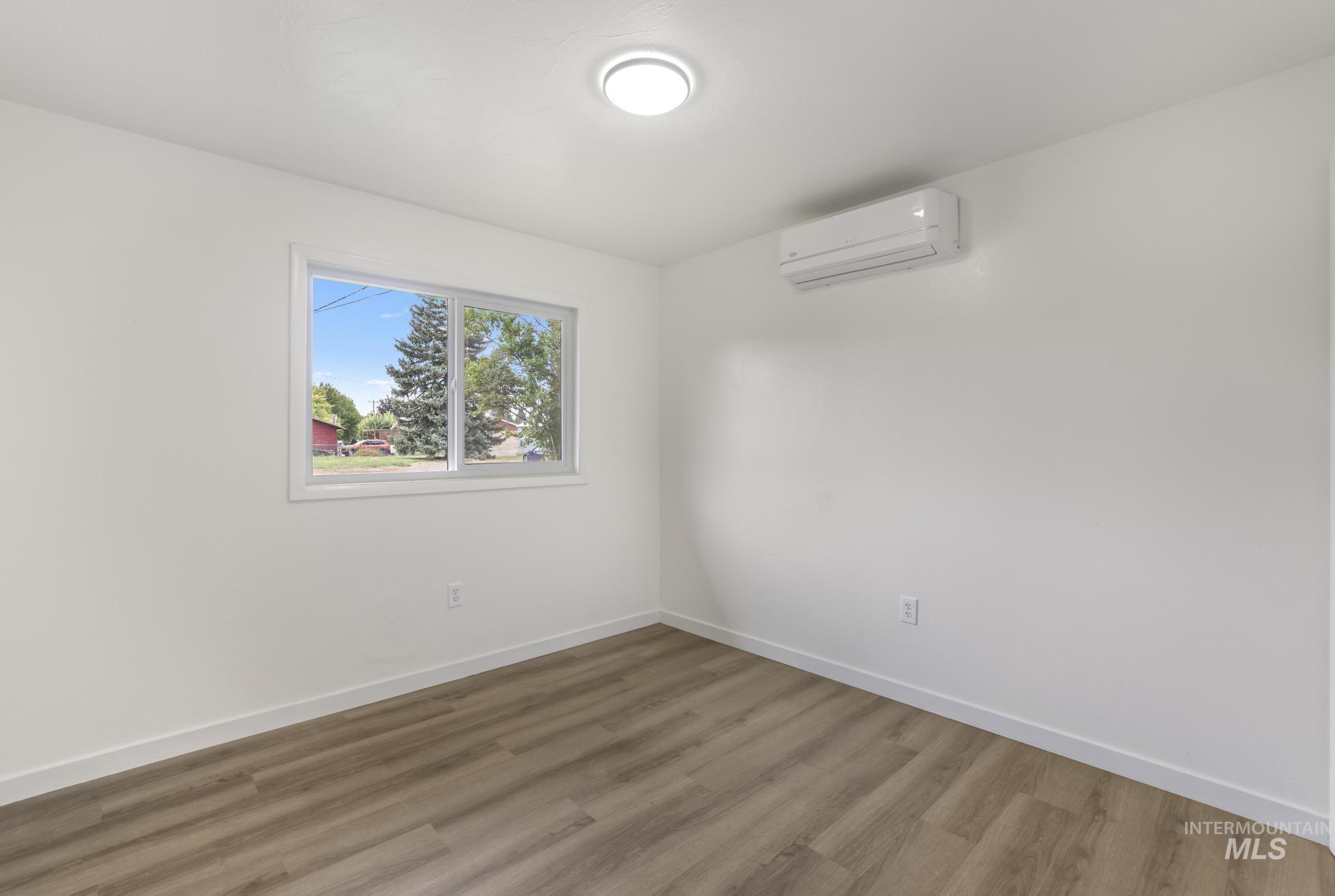 Unfurnished room with wood finished floors and a wall mounted air conditioner