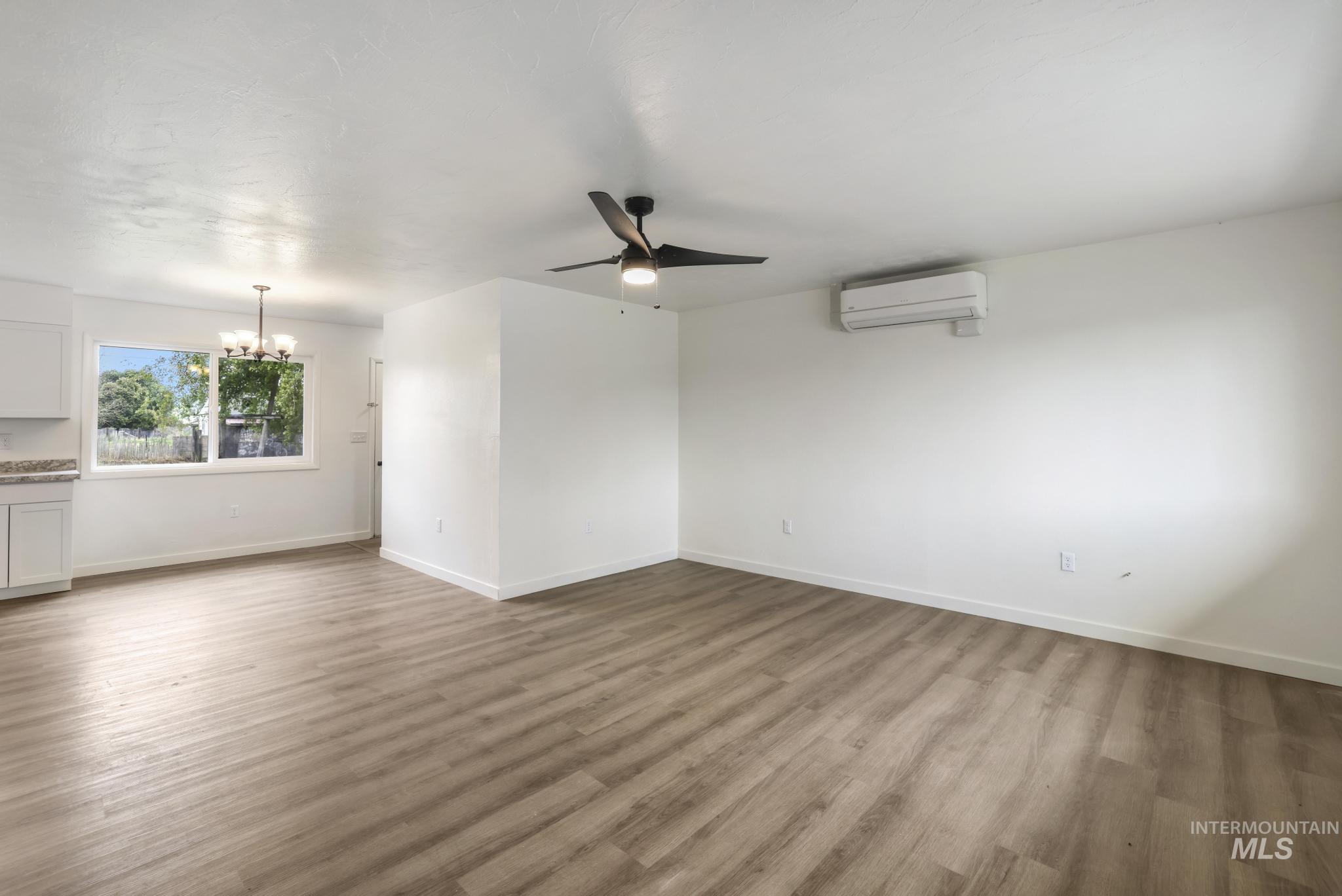 Great Room featuring a ceiling fan, light wood-style floors, a chandelier, and a wall mounted AC