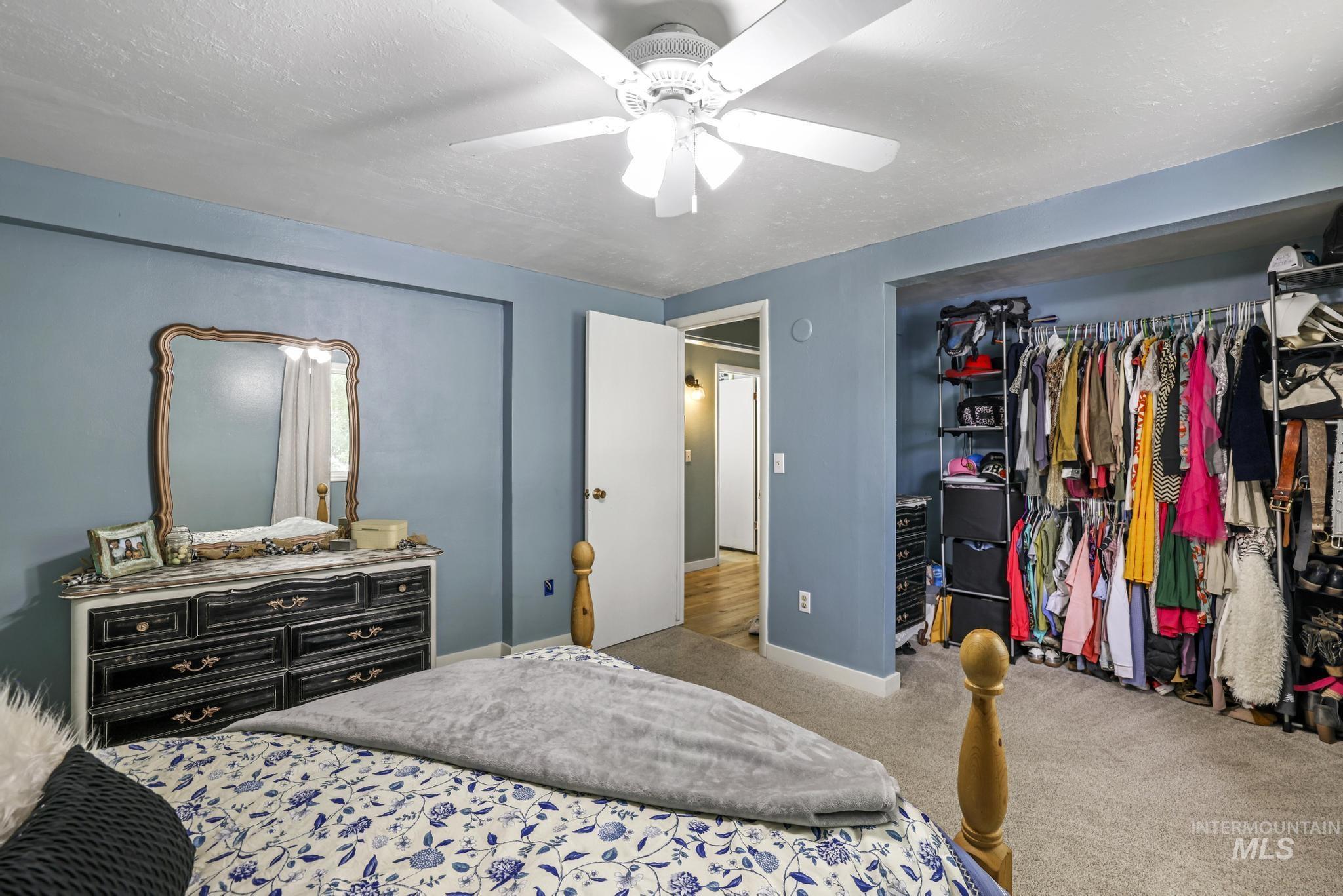 Bedroom with a closet, carpet floors, a ceiling fan, and a textured ceiling