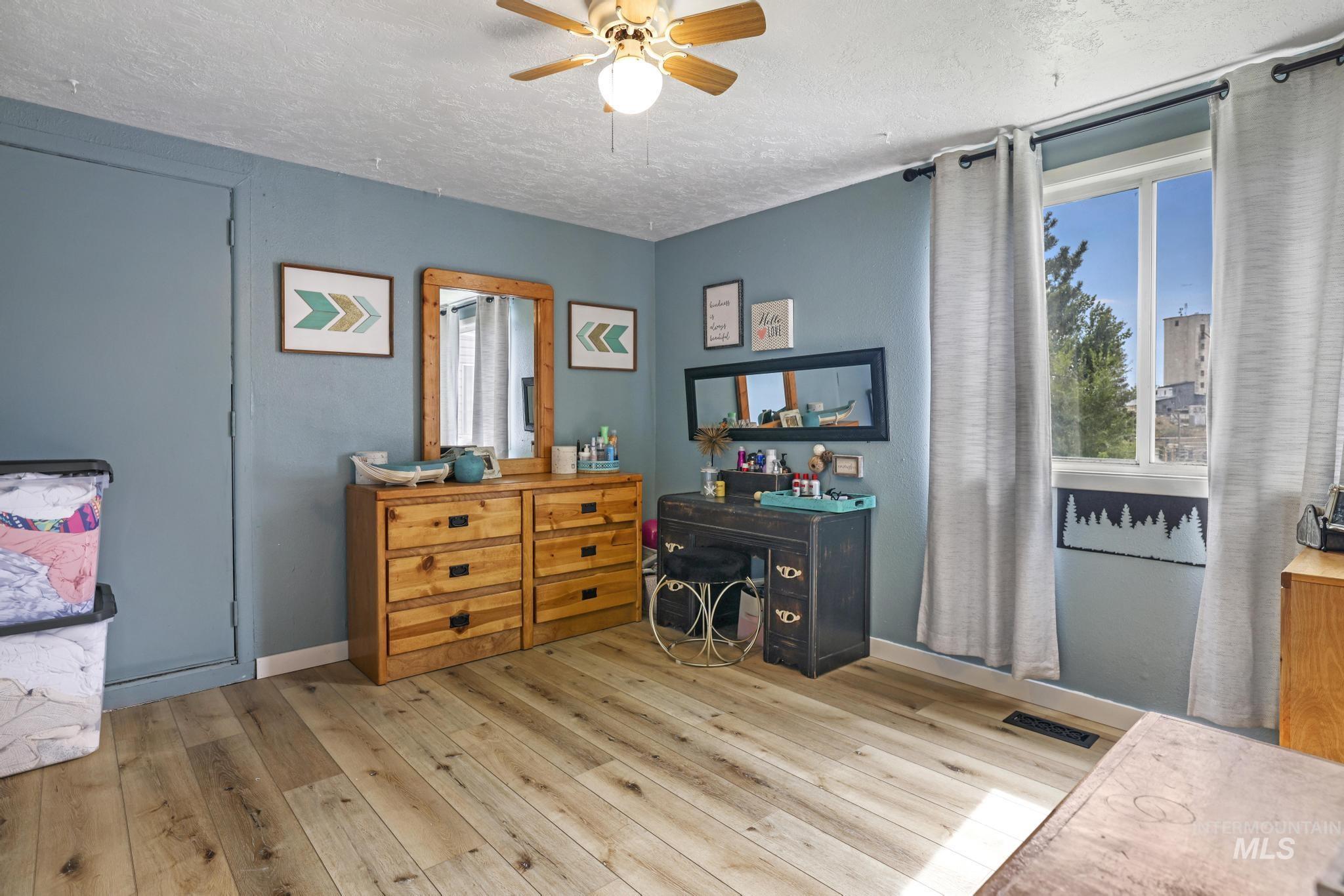 Home office with a textured ceiling, hardwood / wood-style floors, and a ceiling fan