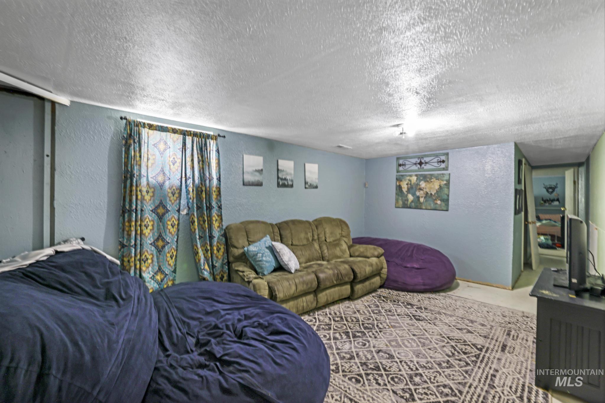 Carpeted living area featuring a textured wall and a textured ceiling