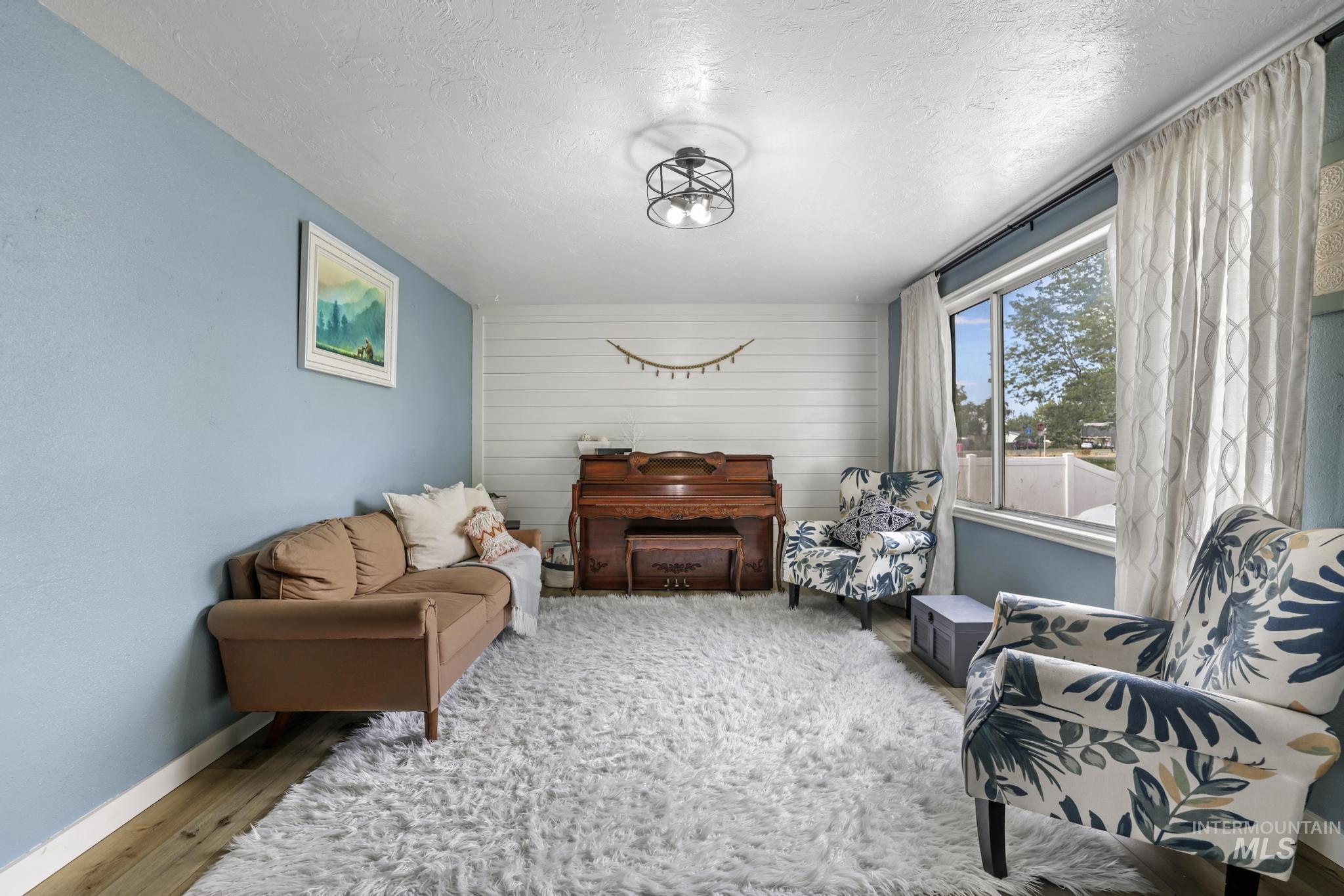 Living area featuring a textured ceiling, wood finished floors, and wood walls