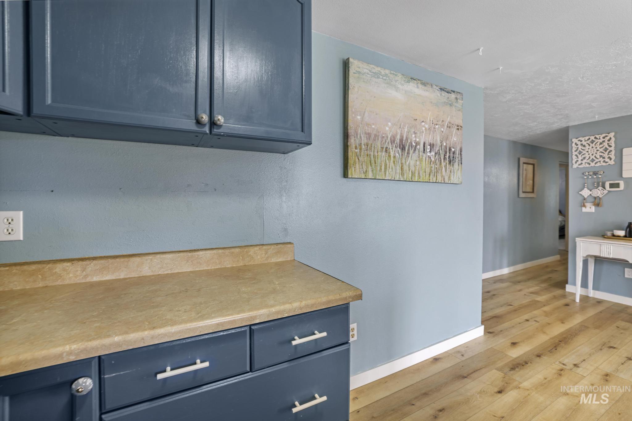Kitchen featuring blue cabinetry, light countertops, and light wood finished floors