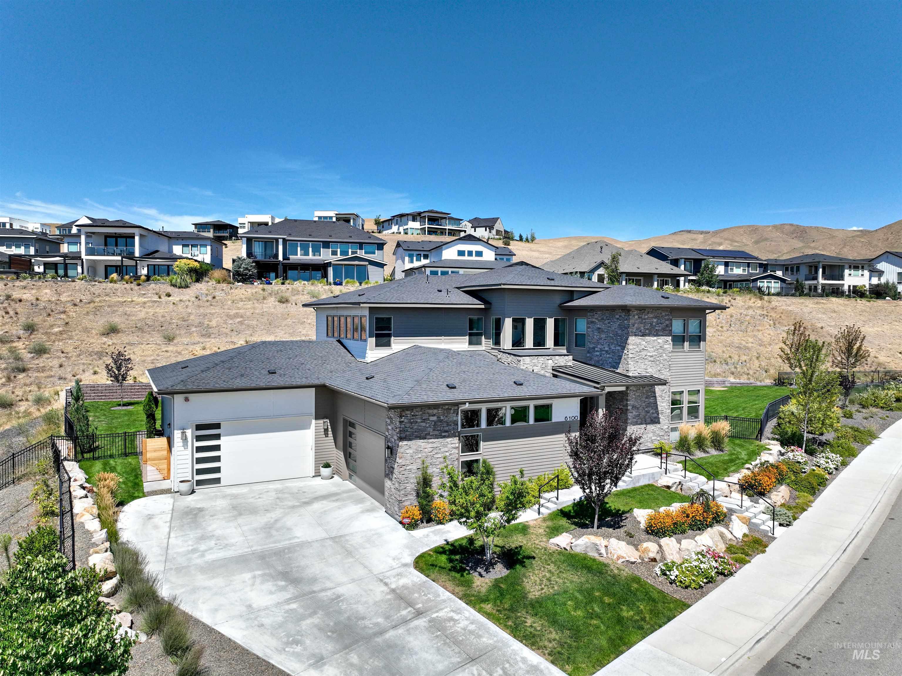 Prairie-style home with a residential view, stone siding, driveway, and an attached garage