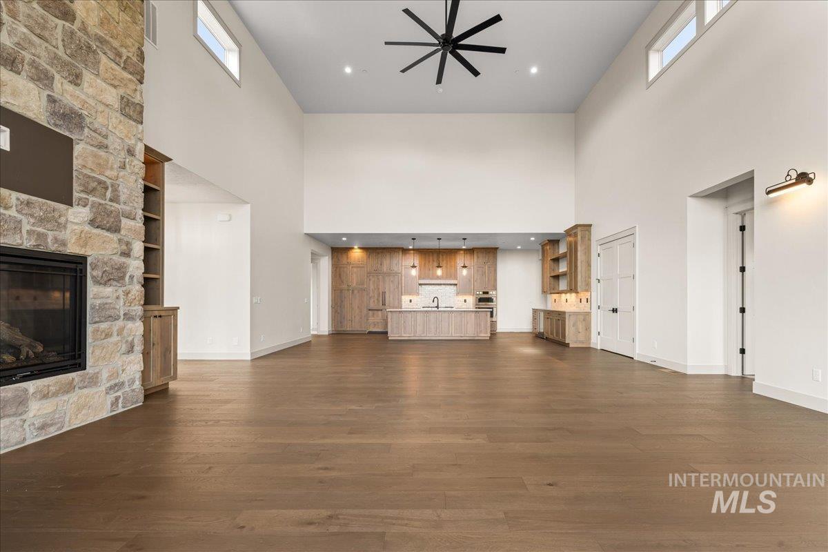 Unfurnished living room featuring a fireplace, dark wood finished floors, a high ceiling, and recessed lighting