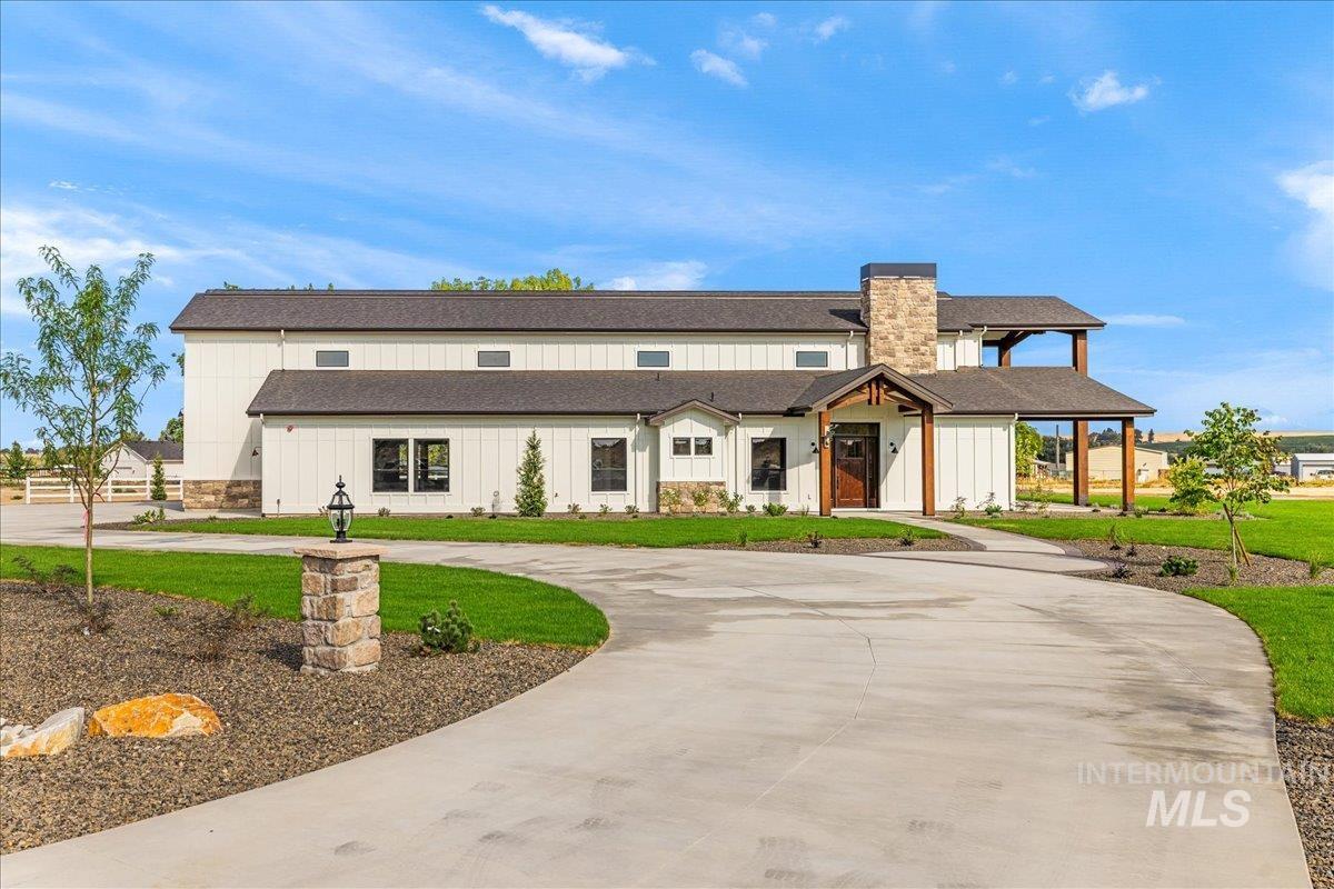 Modern inspired farmhouse featuring curved driveway, a shingled roof, board and batten siding, and a front lawn