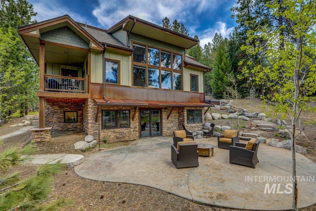Rear view of house with a patio area, stone siding, a balcony, and an outdoor living space with a fire pit