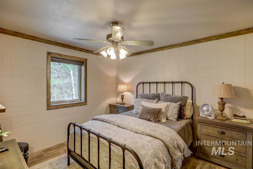 Bedroom featuring ceiling fan, wood finished floors, and a textured ceiling