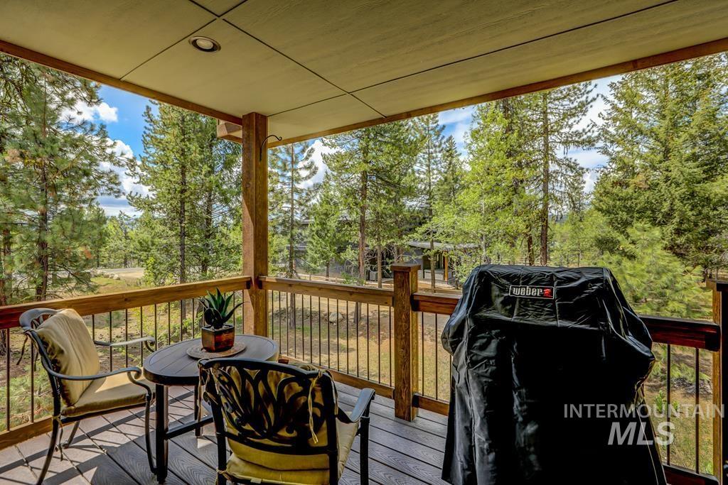 Wooden terrace featuring area for grilling and view of scattered trees
