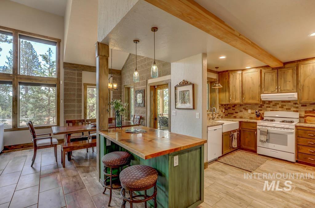 Kitchen featuring butcher block countertops, white appliances, a kitchen bar, pendant lighting, and brown cabinets
