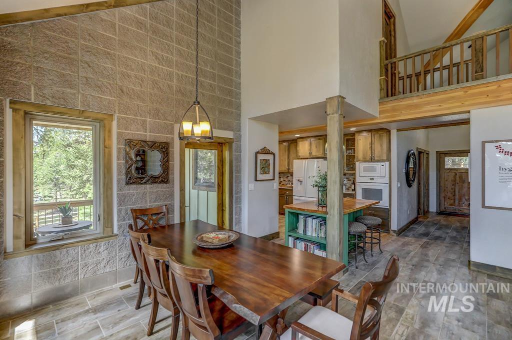 Dining area with healthy amount of natural light, high vaulted ceiling, light wood-style flooring, and a chandelier