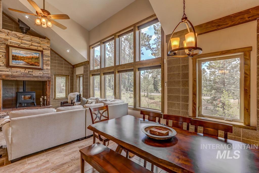 Dining area featuring a wood stove, high vaulted ceiling, a ceiling fan, light wood finished floors, and a chandelier