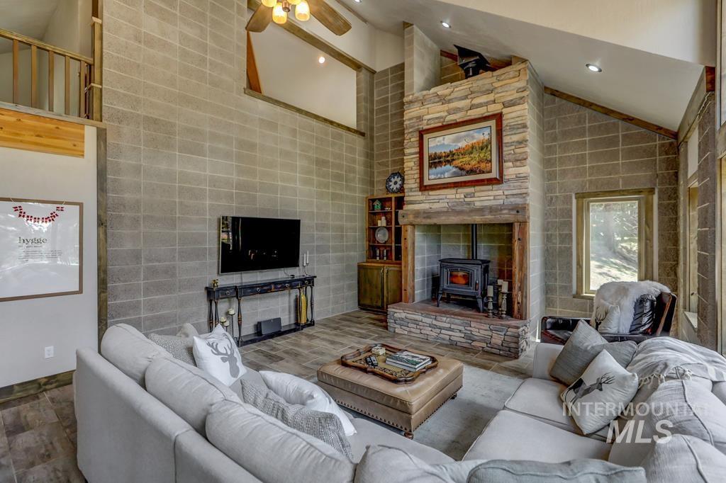 Living room with a wood stove, high vaulted ceiling, ceiling fan, and recessed lighting