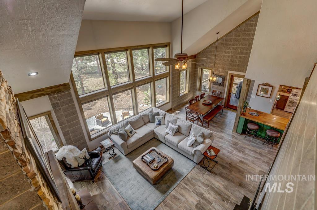 Living room featuring high vaulted ceiling, ceiling fan, and wood finished floors