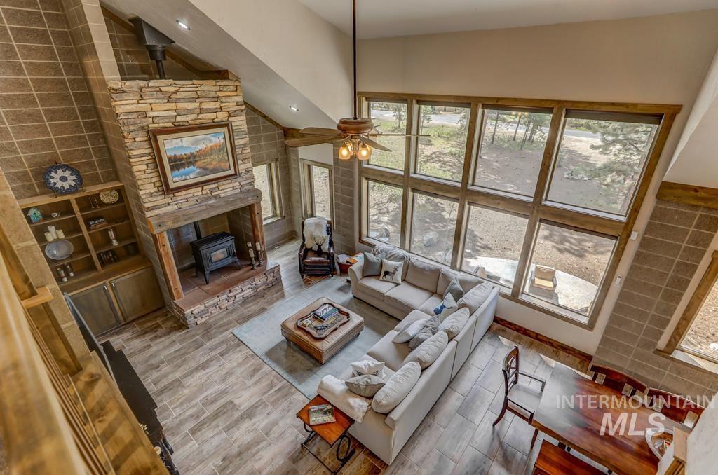 Living area with a wood stove, wood tiled floors, ceiling fan, and a high ceiling