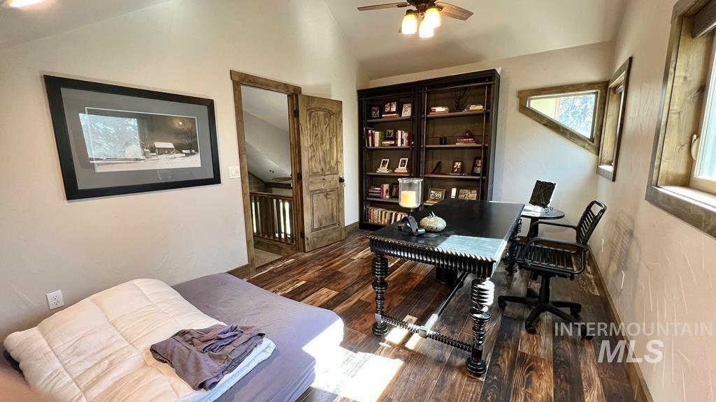 Office area with vaulted ceiling, dark wood finished floors, and a ceiling fan