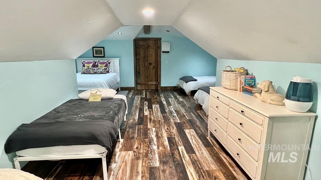 Bedroom with vaulted ceiling and dark wood-style flooring