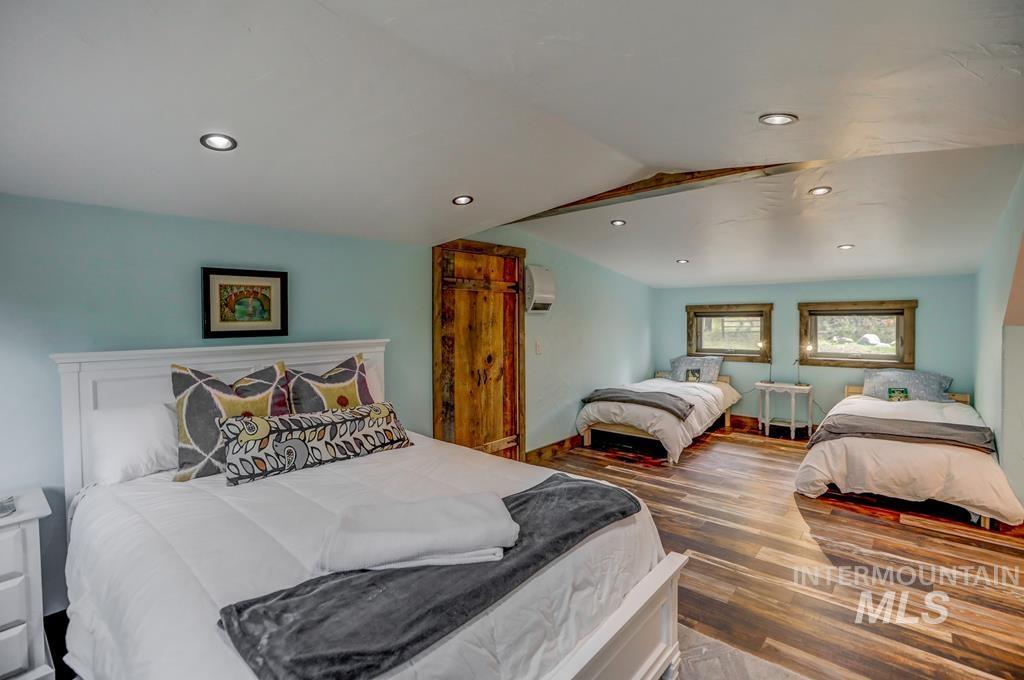Bedroom with vaulted ceiling, wood finished floors, and recessed lighting