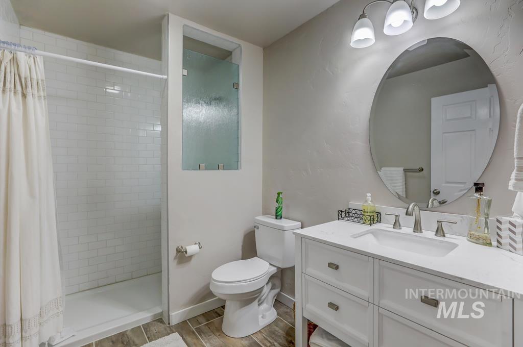 Full bath with vanity, a stall shower, and wood tiled floors