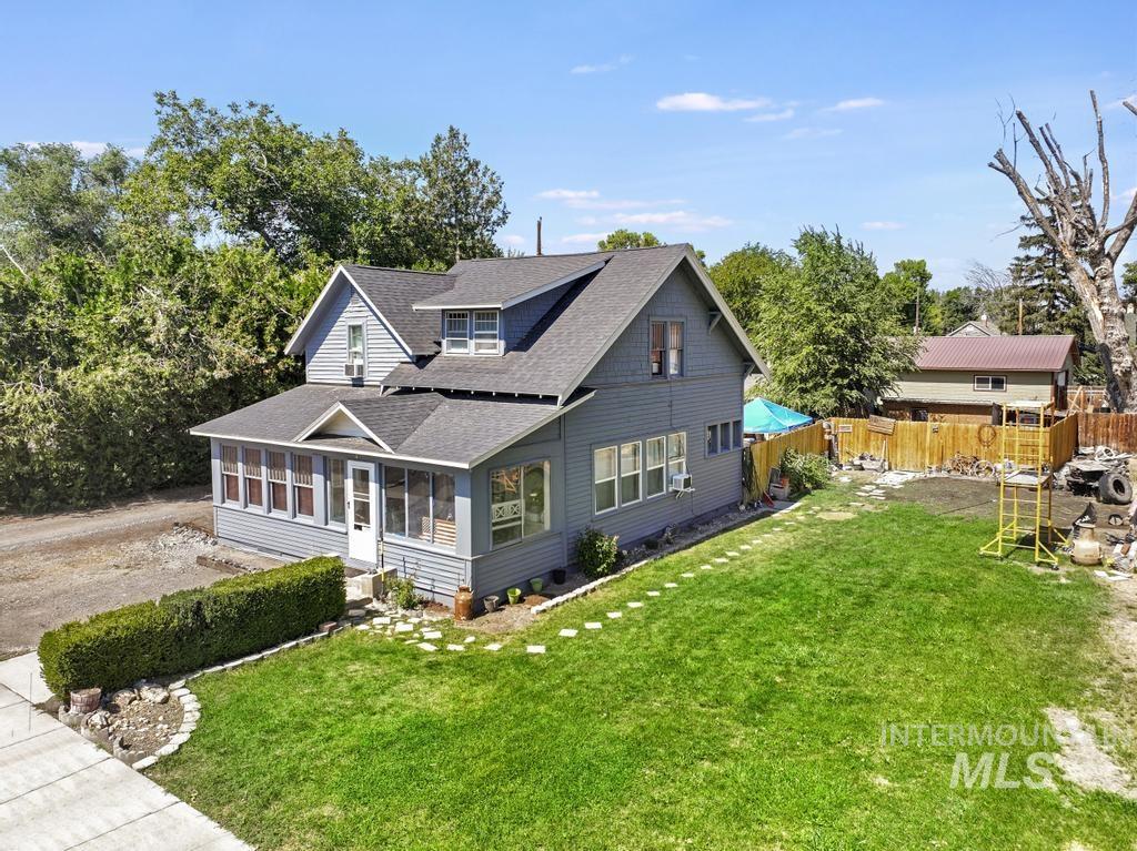 View of front of property featuring a sunroom and a shingled roof