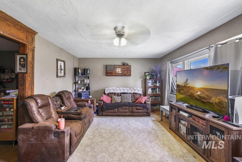 Living area with a textured ceiling, wood finished floors, and a ceiling fan