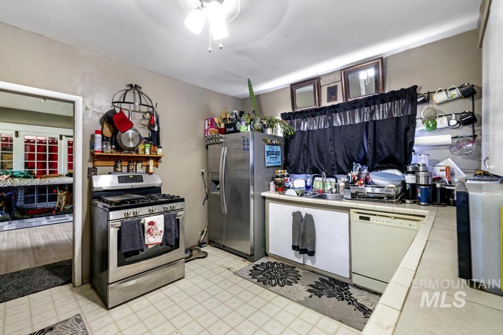 Kitchen with tile counters, appliances with stainless steel finishes, and light floors