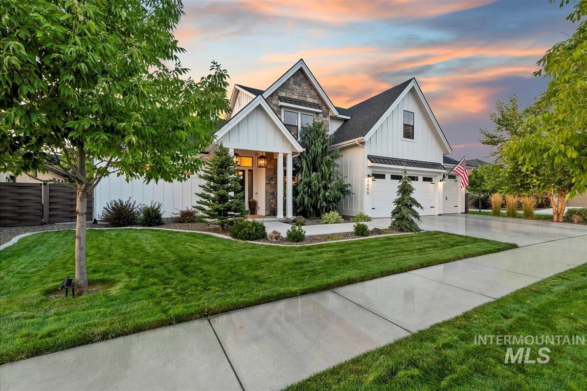 Modern inspired farmhouse featuring board and batten siding, a standing seam roof, concrete driveway, stone siding, and a metal roof