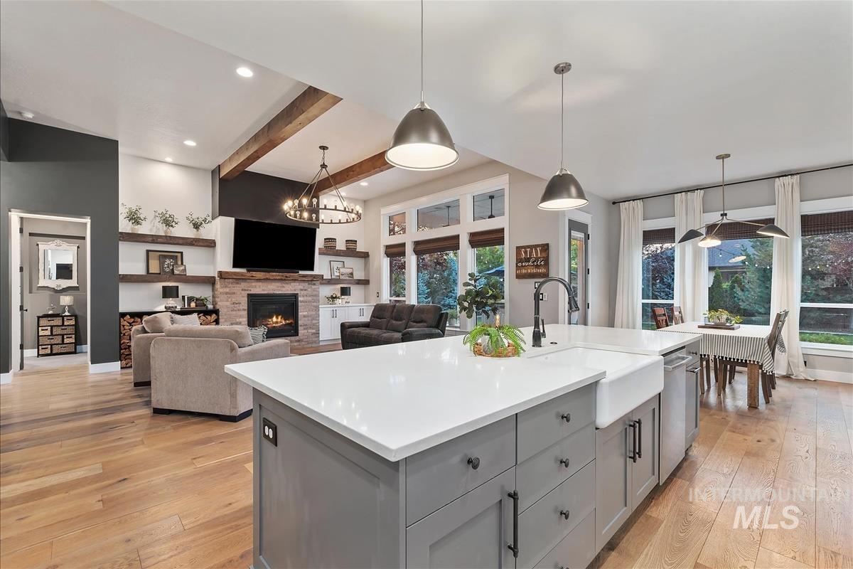 Kitchen with a chandelier, beamed ceiling, gray cabinets, hanging light fixtures, and light wood-style floors