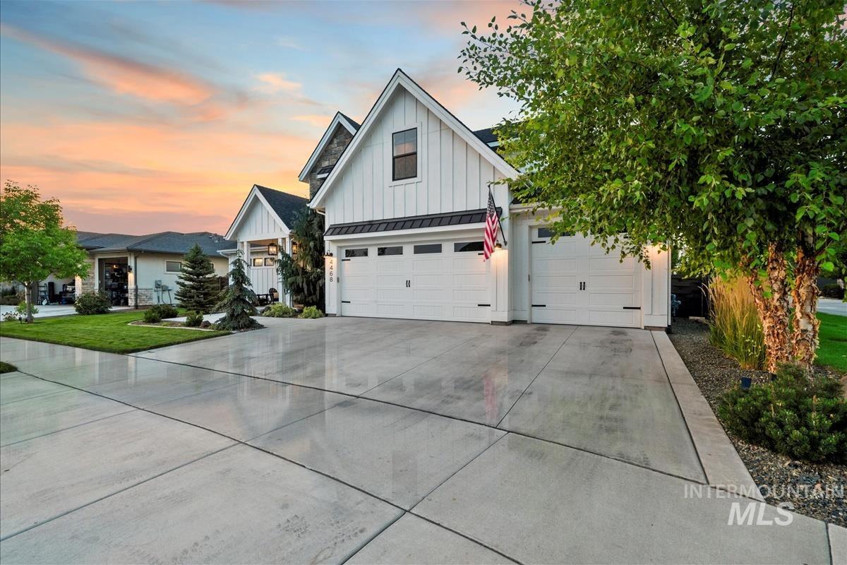 Modern farmhouse with board and batten siding, a standing seam roof, a metal roof, driveway, and a garage