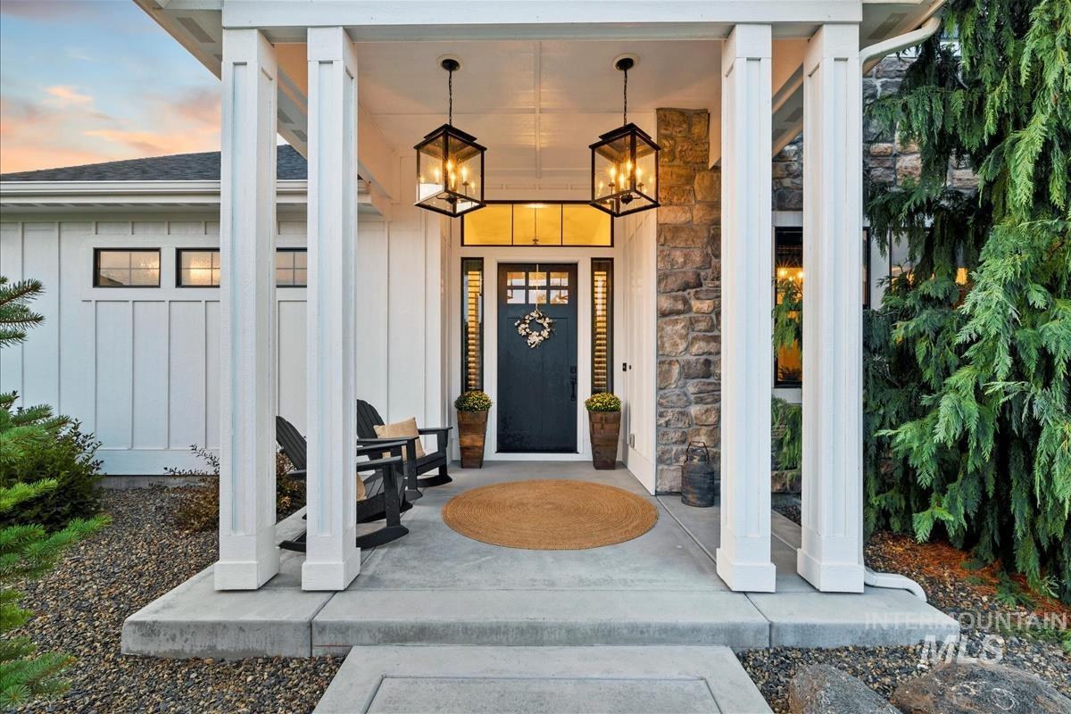 Exterior entry at dusk featuring board and batten siding, covered porch, and stone siding