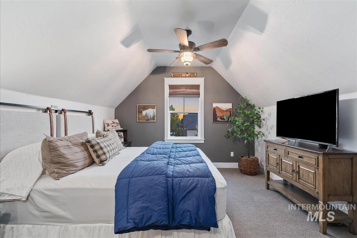 Carpeted bedroom featuring ceiling fan and lofted ceiling