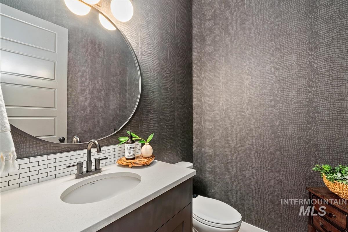 Half bathroom featuring vanity and decorative backsplash