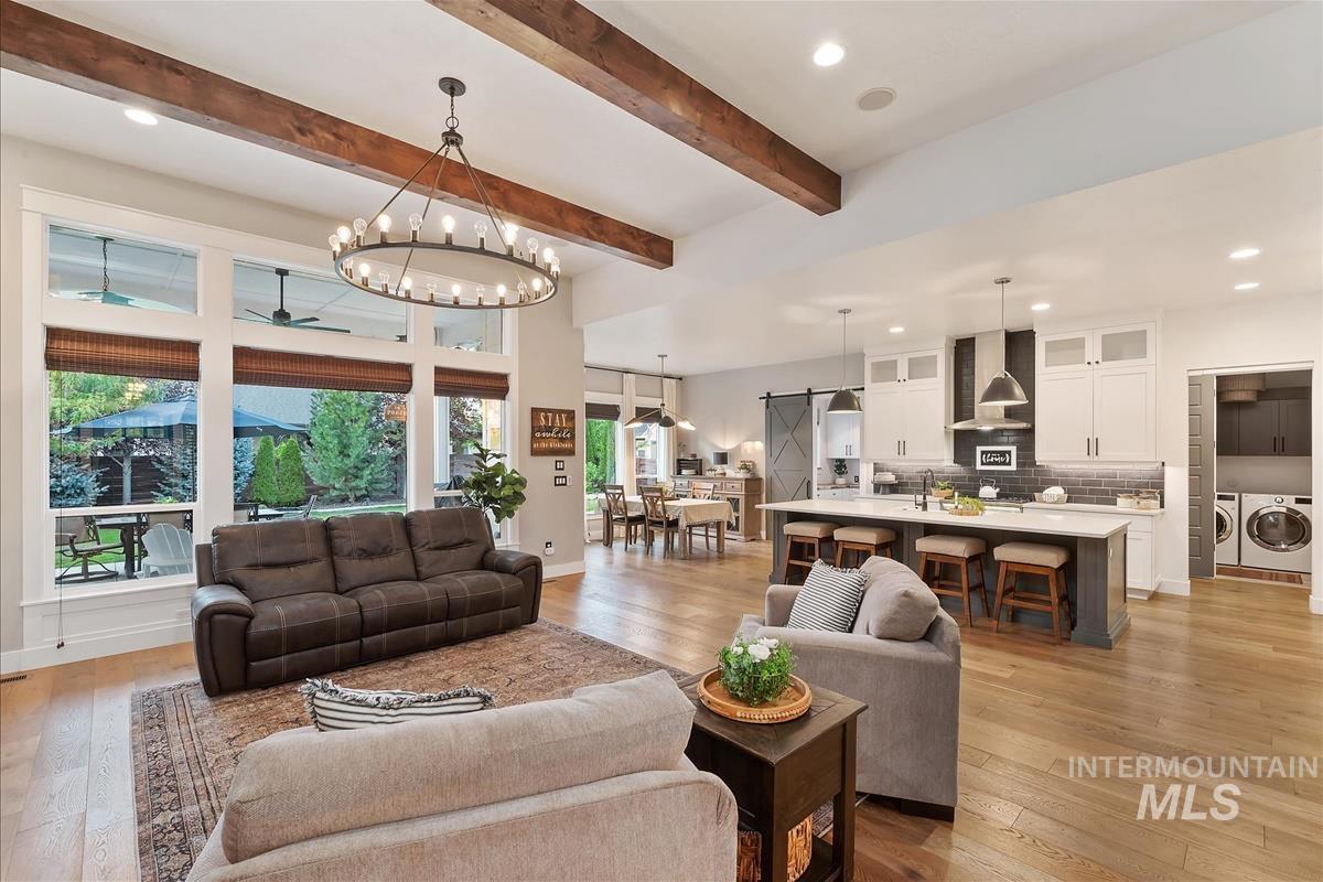 Living room featuring a barn door, recessed lighting, light wood-style floors, ceiling fan, and a chandelier