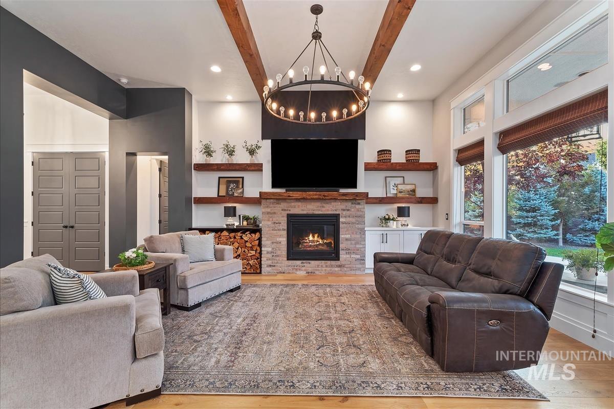 Living area featuring beamed ceiling, wood finished floors, a fireplace, recessed lighting, and a chandelier