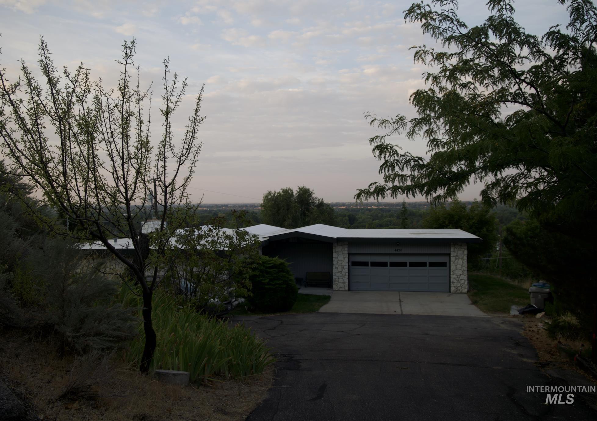 View of front facade with driveway, stone siding, and a garage