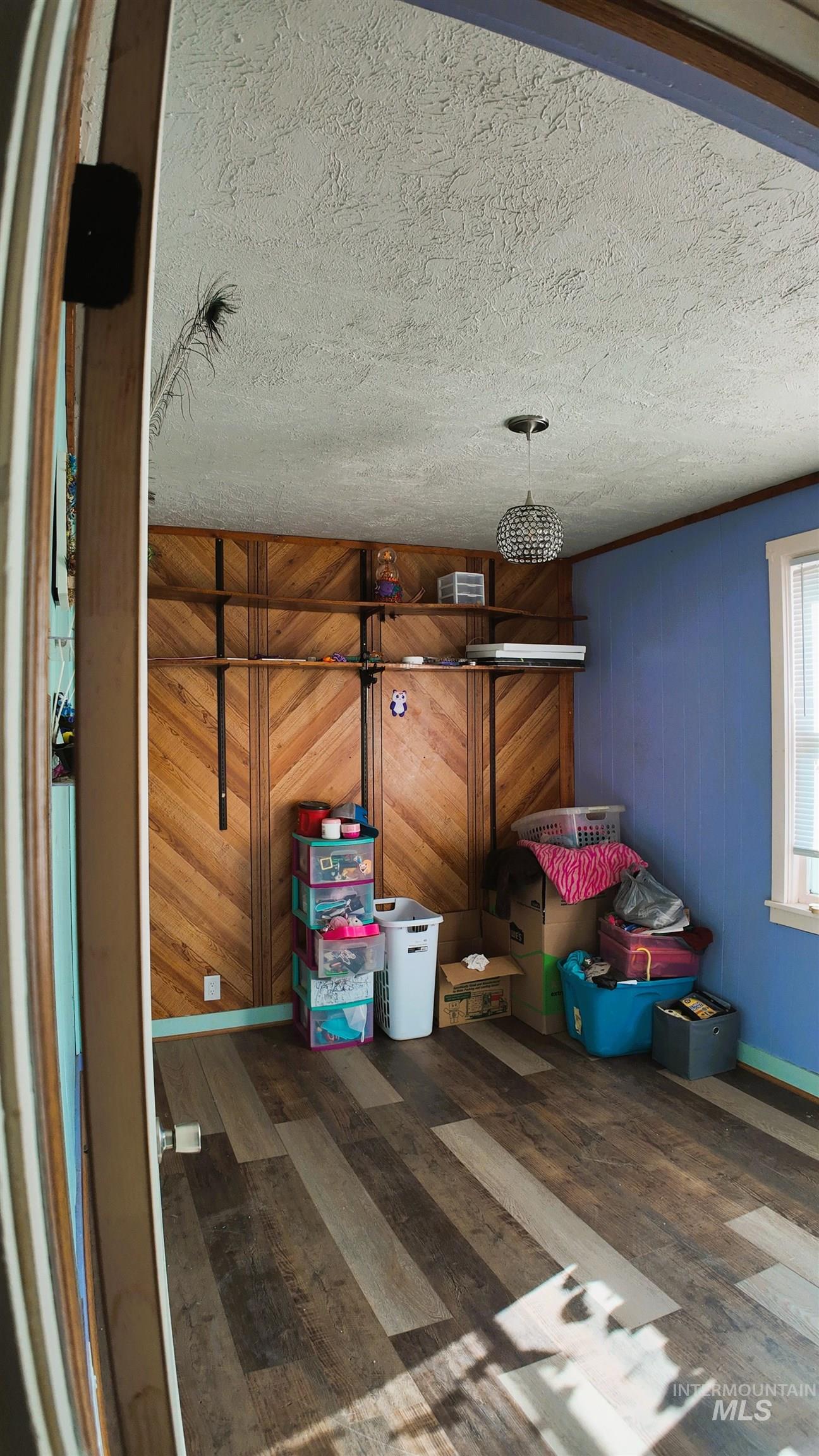 Detailed view of wooden walls, wood finished floors, and a textured ceiling