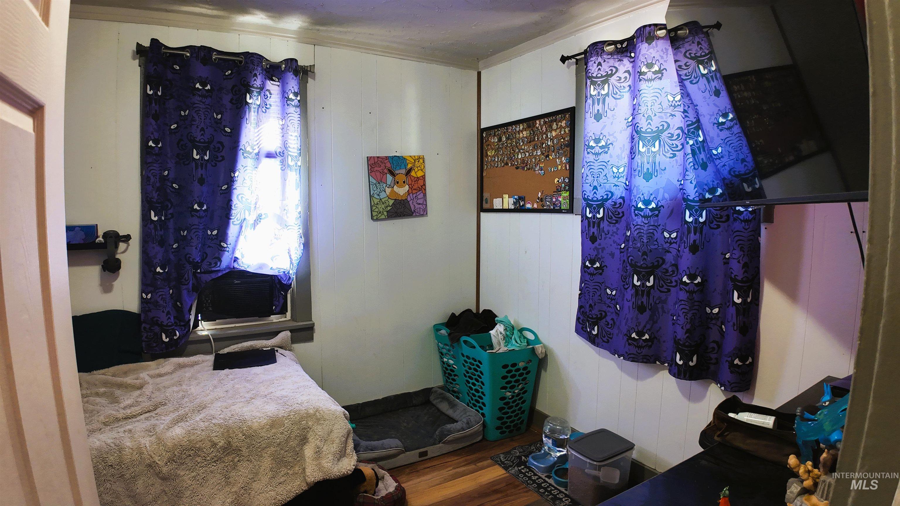 Bedroom with wood finished floors and wooden walls