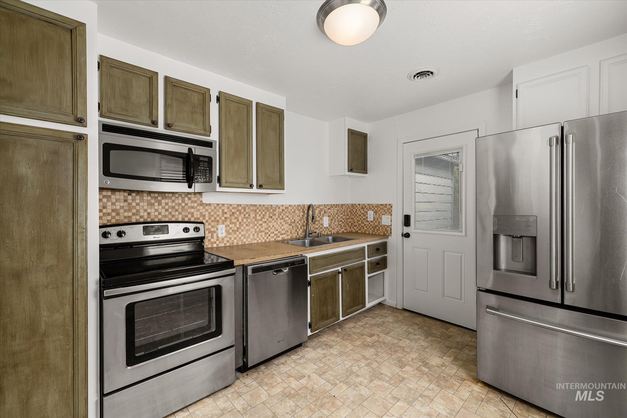 Kitchen with stainless steel appliances and backsplash