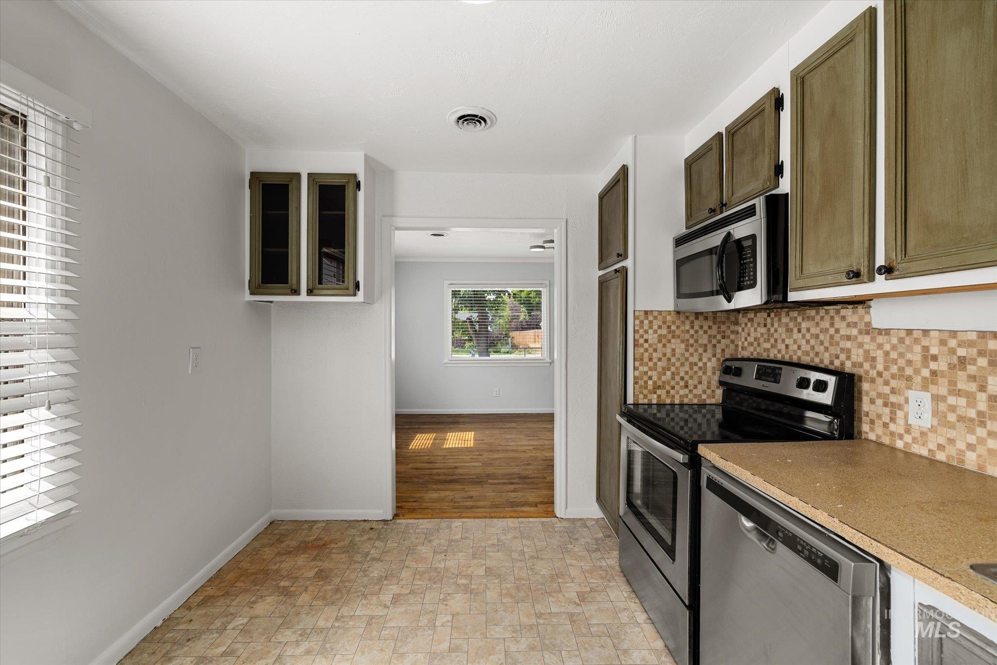 Kitchen featuring stainless steel appliances, tasteful backsplash, and stone finish flooring