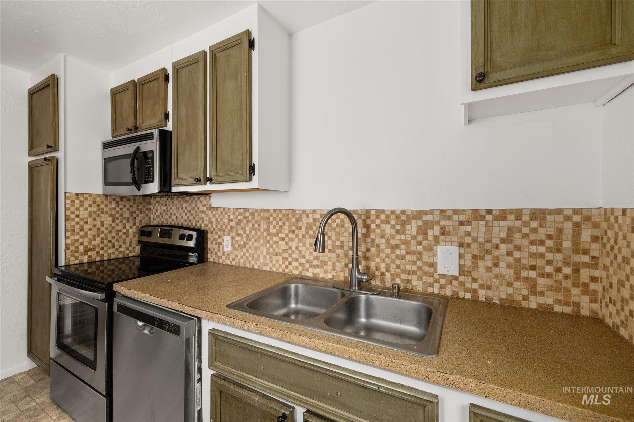 Kitchen with stainless steel appliances and tasteful backsplash