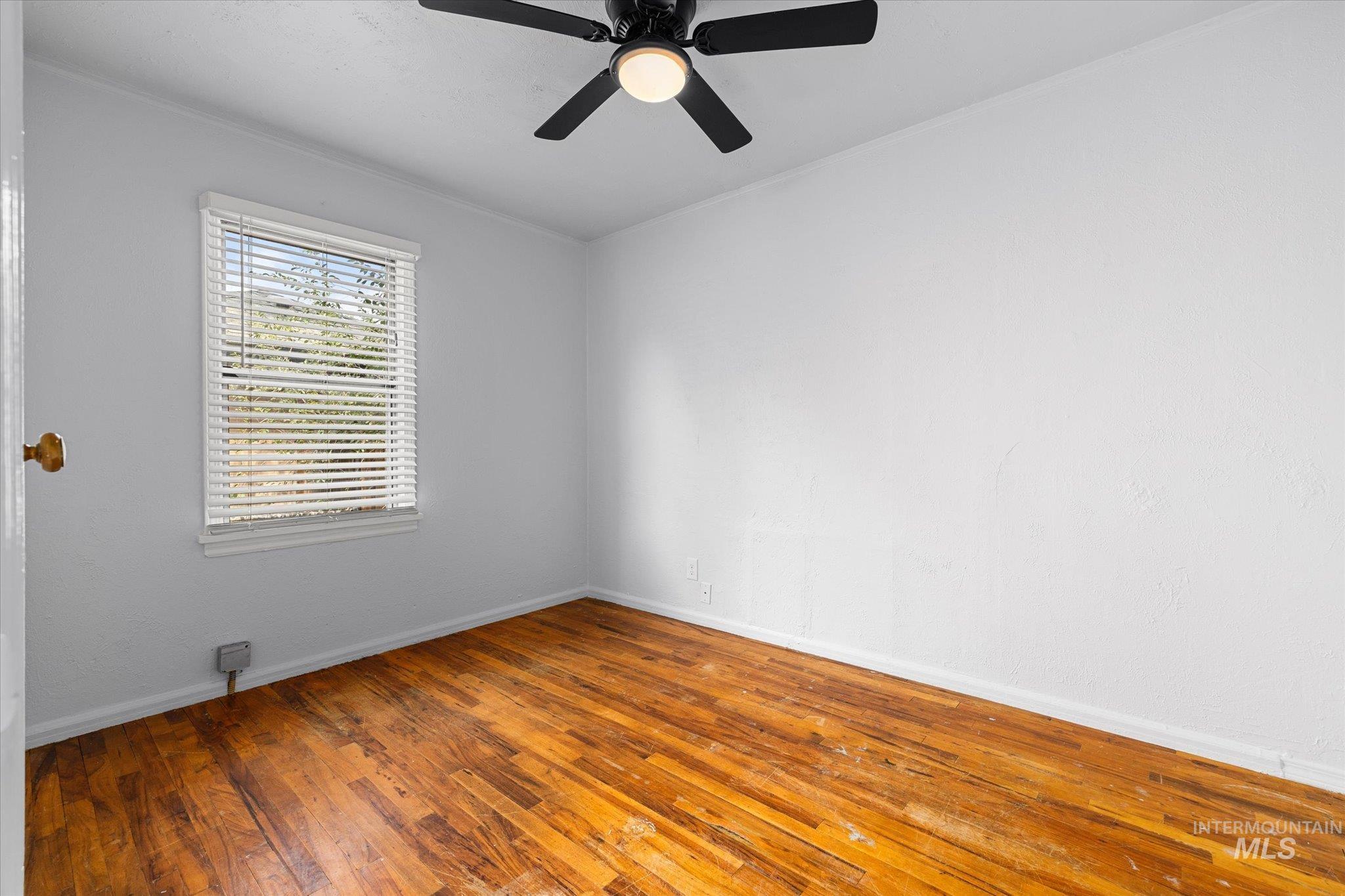 Unfurnished room featuring hardwood / wood-style floors, crown molding, and ceiling fan