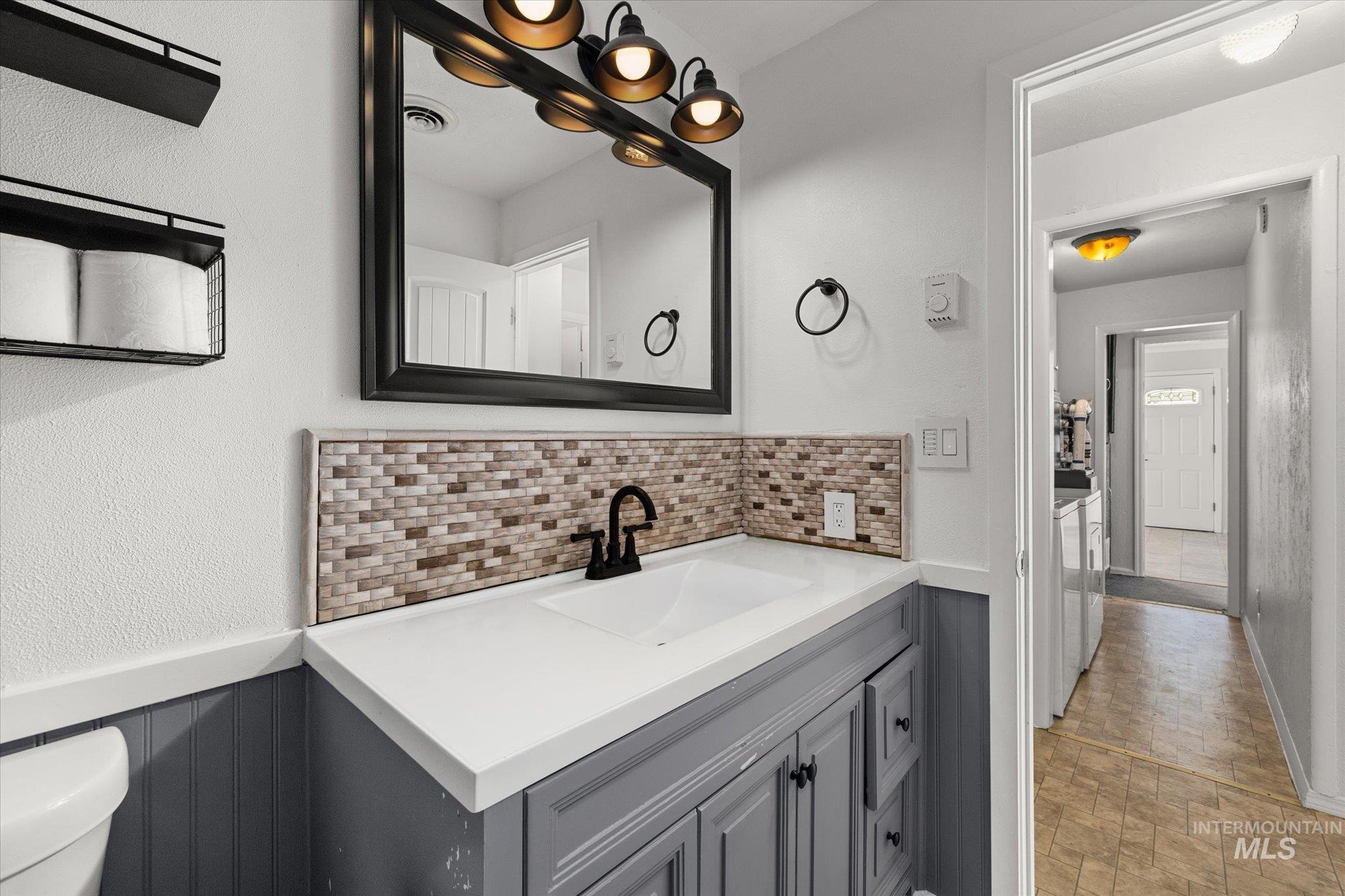 Half bath with vanity, backsplash, and a textured wall