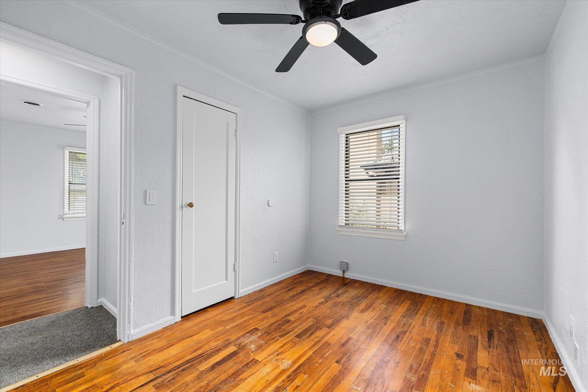 Unfurnished bedroom with hardwood / wood-style floors, a ceiling fan, and ornamental molding